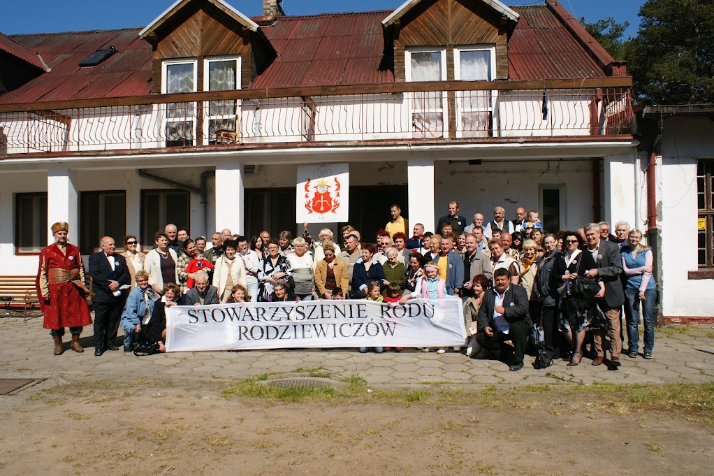 Zdjęcie grupowe uczestników Zjazdu Rodziewiczów przed budynkiem z banerem rodowym